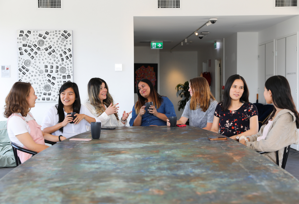group of women sitting around a table talking to each other